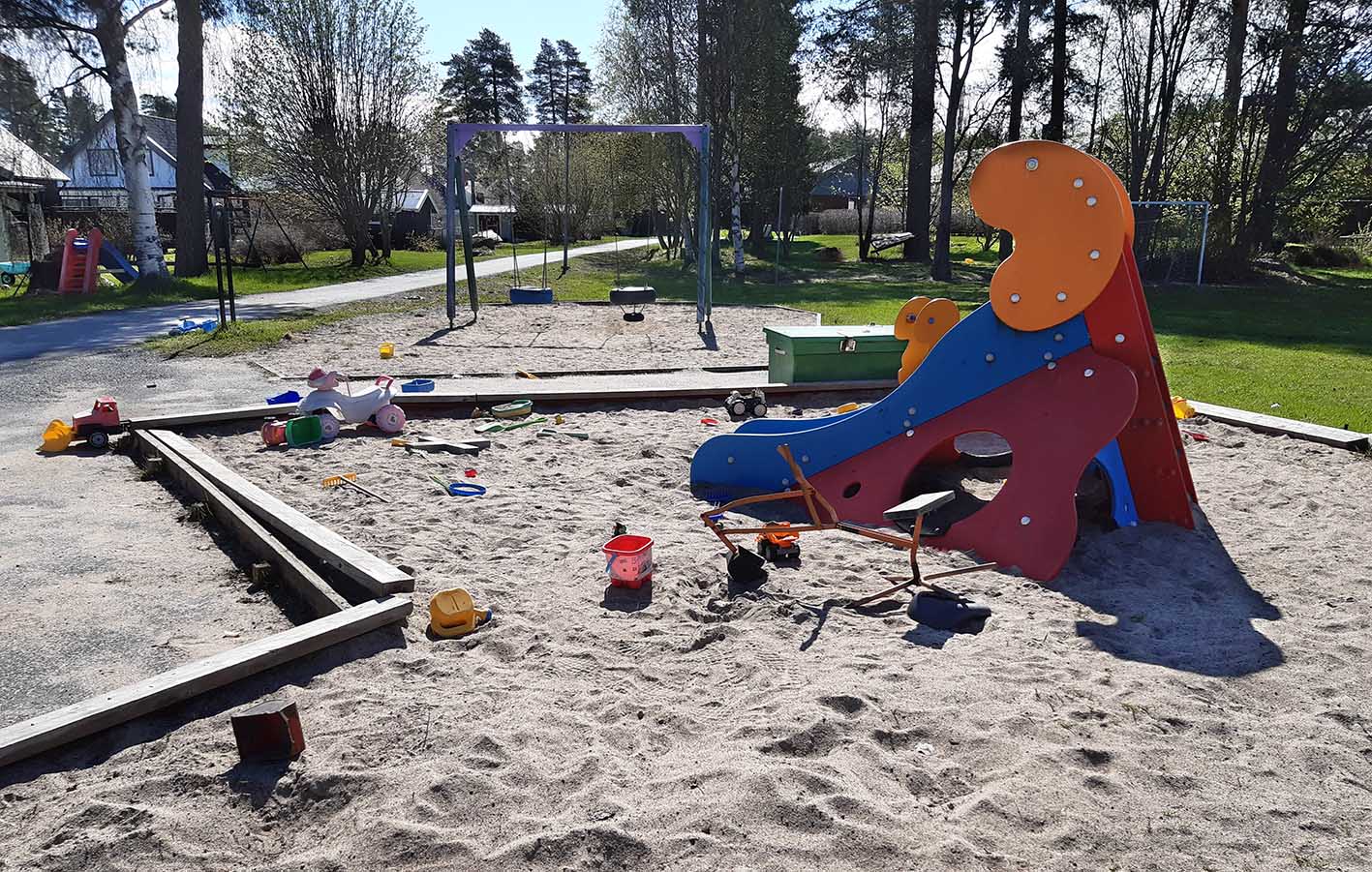 Lektorn med rutschkana med sand under. Många små leksaker i sanden. Gungor i bakgrunden