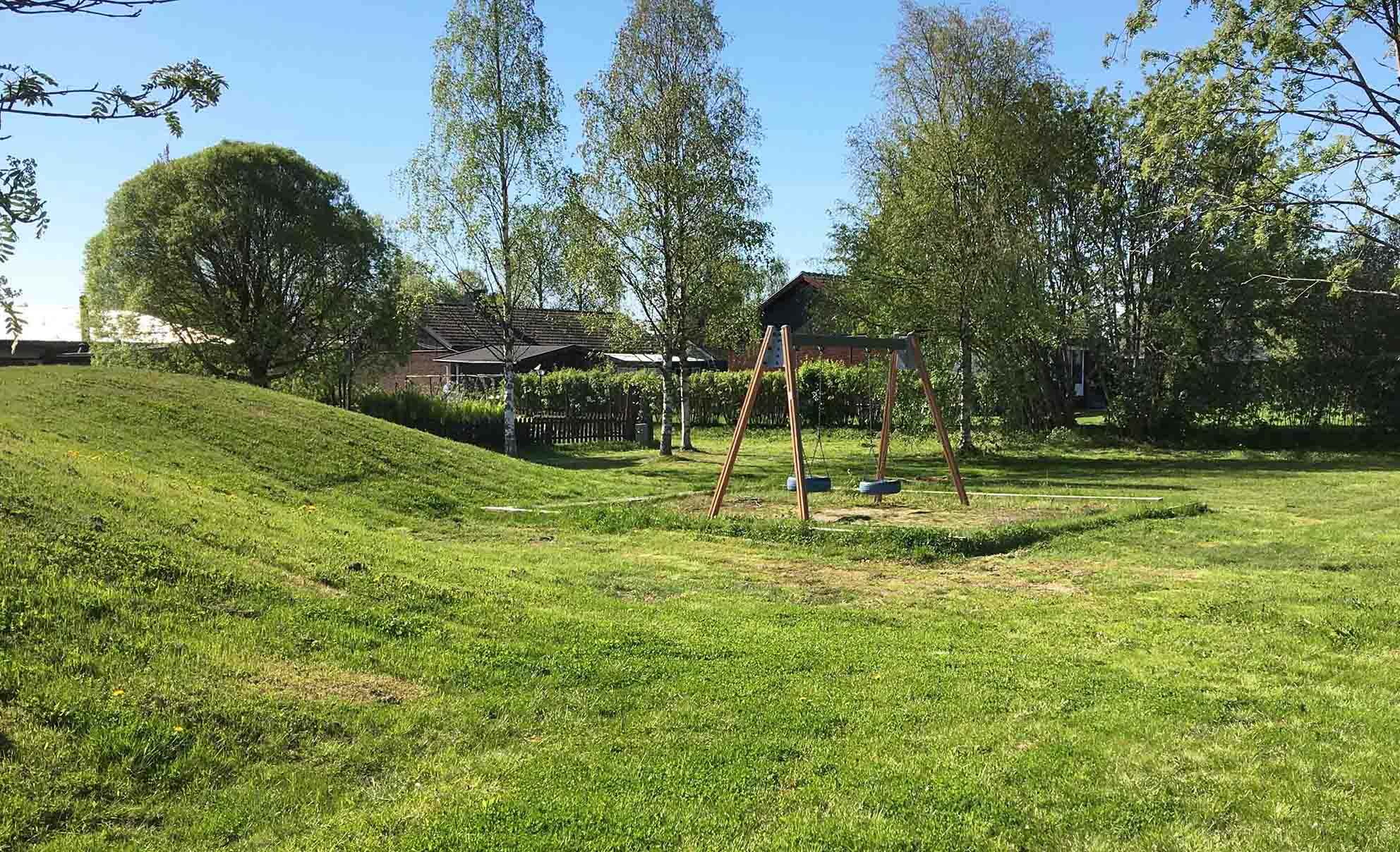 Gungor som står mitt på gräsmattan med gröna kullar omkring